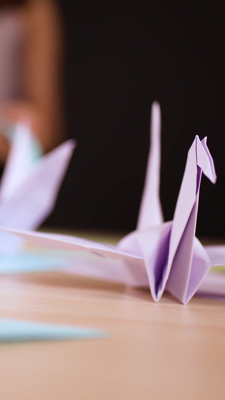 A detailed close-up shot of a completed purple paper crane sitting on a desk