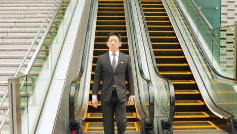 un hombre de negocios japonés tomando la escalera mecánica.