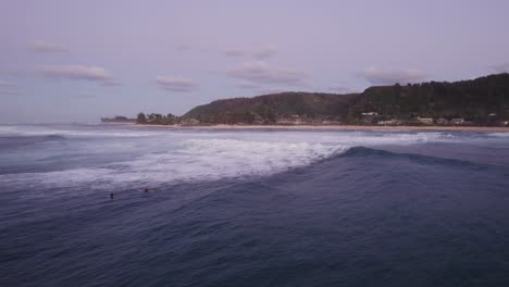 Una-Impresionante-Vista-Aérea-De-Surfistas-Montando-Las-Olas-Durante-La-Puesta-De-Sol-En-La-Costa-Norte-De-Oahu,-Hawai