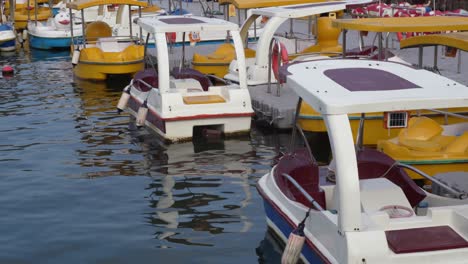 Numerous-pedal-boats-for-hire-sit-idle-on-river-water-waiting-on-people