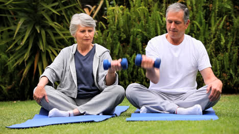 Pareja-Mayor-Haciendo-Ejercicios-Con-Mancuernas-Sobre-Colchonetas-De-Gimnasio