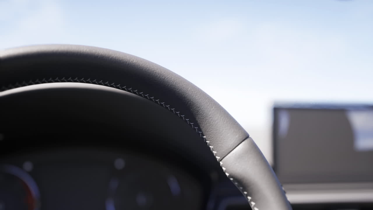 開けた地形の道を晴れた日に運転中のハンドルを間近で見た様子。
