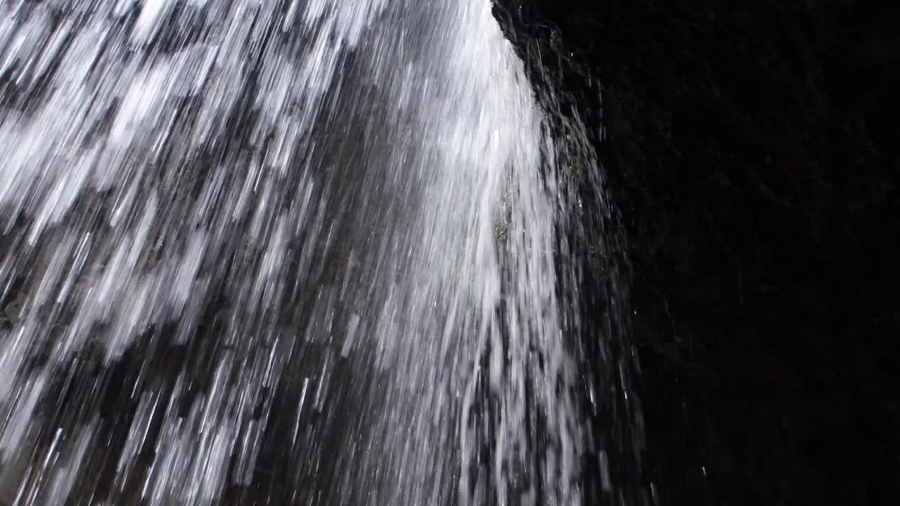 Close view of fast flowing mountain stream of waterfall from cliff