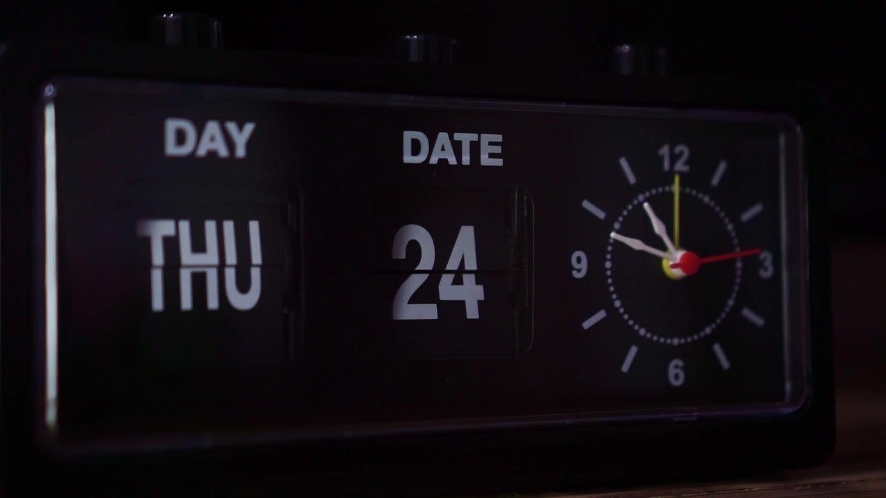 retro flip clock with moving second hand, day and date display, vintage timepiece in dark room concept.