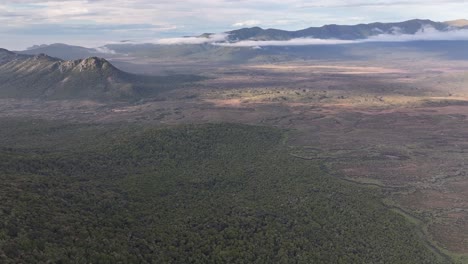 Aerial-wide-opening-shot-of-Rakiura,-Stewart-Island,-native-vegetation,-creek-and-mountains