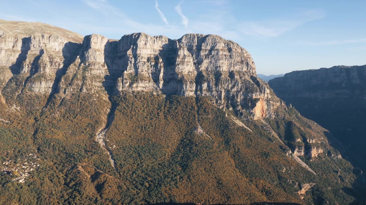 Lenta ripresa con drone che rivela il villaggio di Mikro Papigko a Zagorochoria sotto il sole splendente di primavera. L'Astraka si erge sullo sfondo