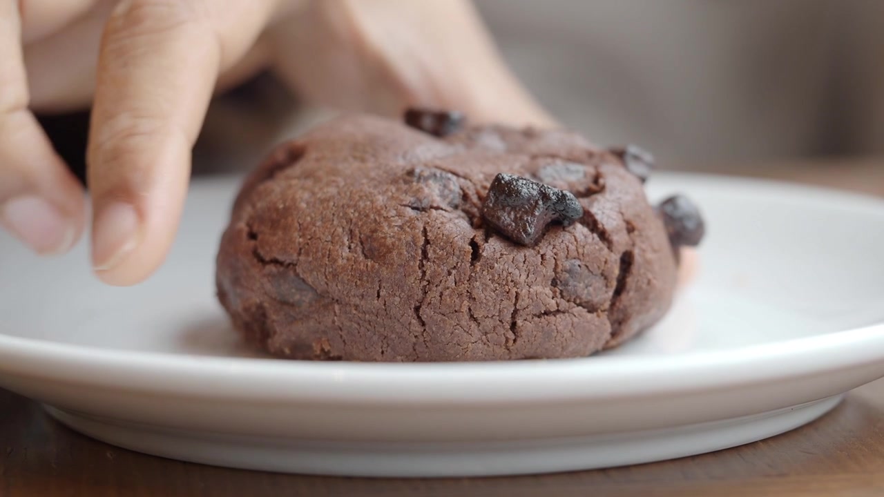 Close-Up of a Hand Picking Up a Chocolate Chip Cookie