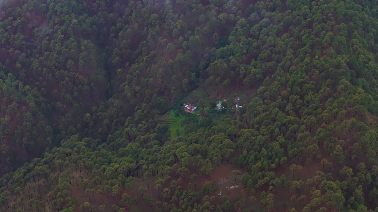 Aerial drone shot of a peaceful mountain scene where fog slowly lifts with the morning light.
