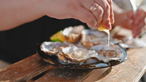 person squeezing lemon juice over oysters