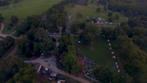 fly over 4k drone slow push in of rural music and art festival on historic farm