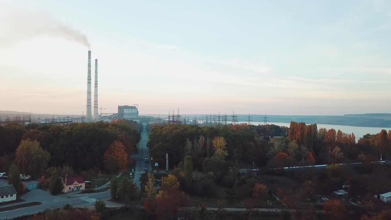 view of the power station with two pipes and with road to it with the planting of trees near the river. Aerial view