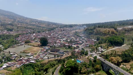 busy village near massive mountain slope, aerial drone view