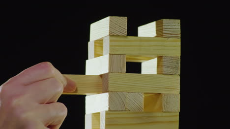 la mano saca un bloque de madera de la torre jugando en el concepto de juegos de mesa djanga