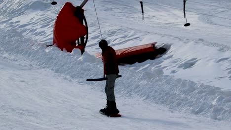 snowboarder being pulled up a slope on a t-bar lift