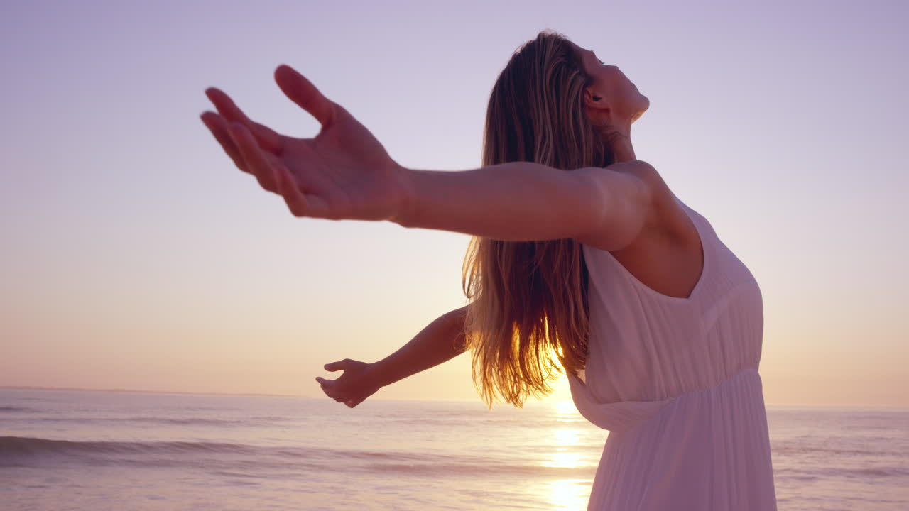 mulher feliz livre braços estendidos desfrutando da natureza na praia ao pôr do sol rosto levantado em direção ao céu grande ângulo câmera lenta dragão vermelho