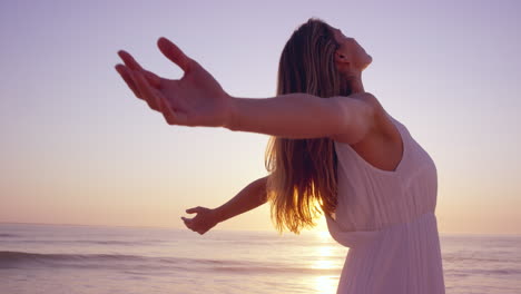 free happy woman arms outstretched enjoying nature on beach at sunset face raised towards sky wide angle slow motion red dragon