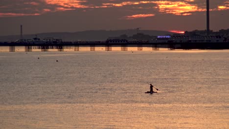 Silueta-Al-Atardecer-Del-Muelle-De-Brighton-Y-El-Hombre-En-La-Tabla-De-Remo