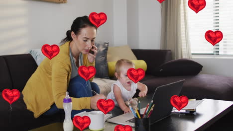 animation of heart icons over caucasian mother with baby talking on smartphone