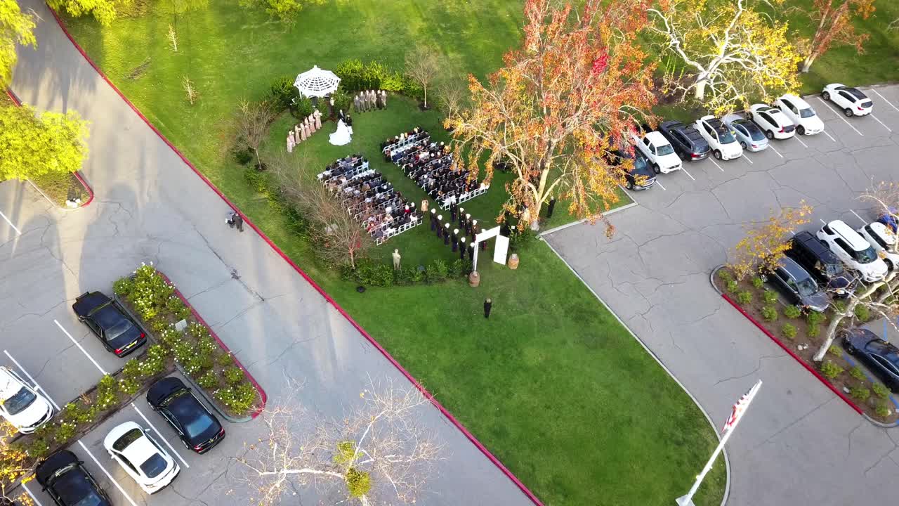 Aerial drone flying into a military outdoor wedding with gazebo with the uniformed Navy officers lined up.