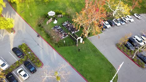 aerial drone flying into a military outdoor wedding with gazebo with the uniformed navy officers lined up.