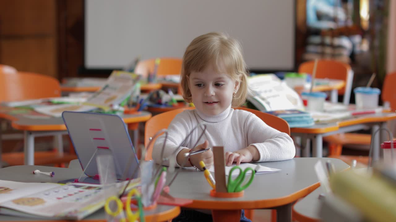 Girl drawing at the table in classroom. Education. Child sitting at a desk