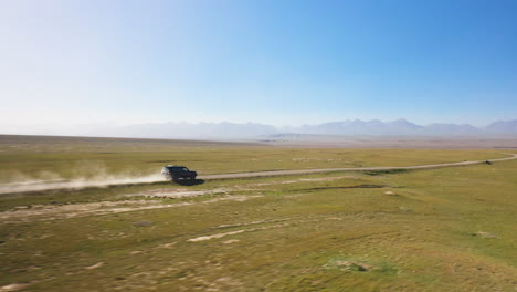 Filmación-Cinematográfica-De-Drones-Que-Va-Al-Lado-De-Un-Todoterreno-Conduciendo-Por-La-Carretera-Cerca-Del-Lago-Kel-suu-En-Kirguistán
