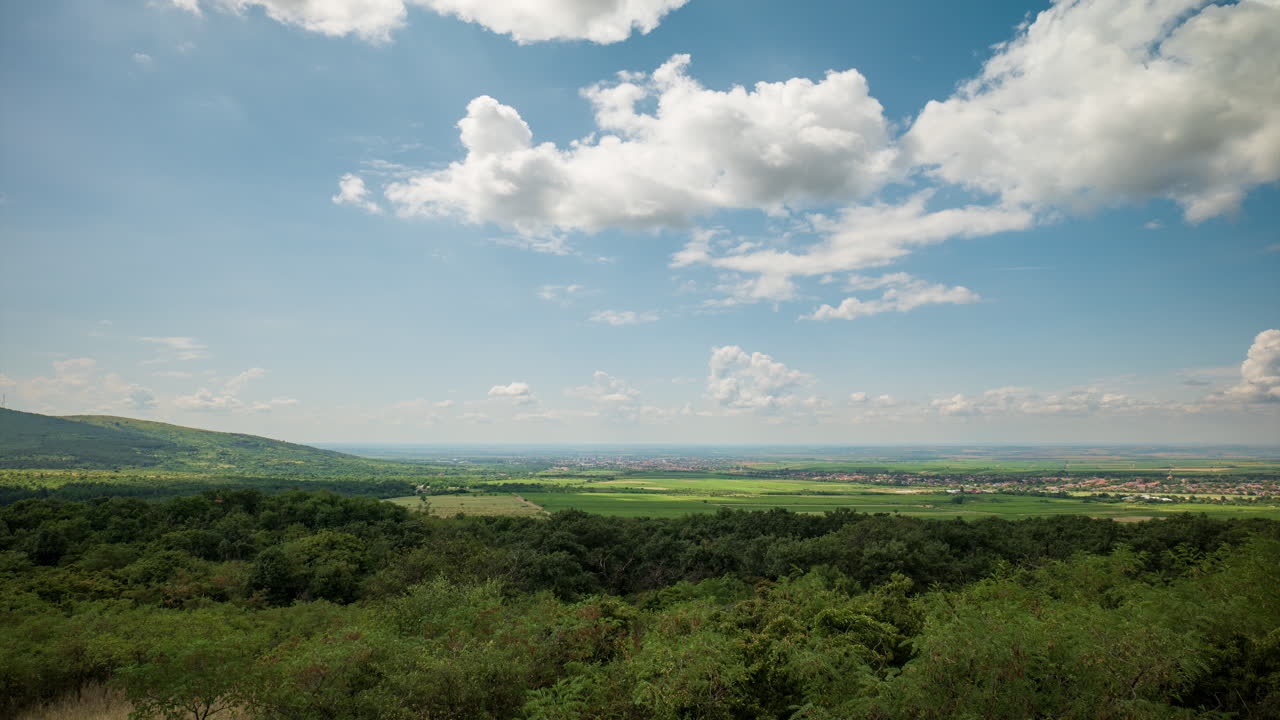 una llanura vista desde las montañas en un día nublado soleado, lapso de tiempo