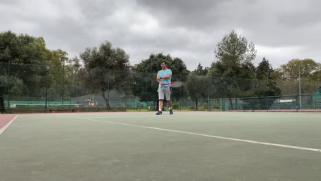 man in white walking on tennis court with racket in hand