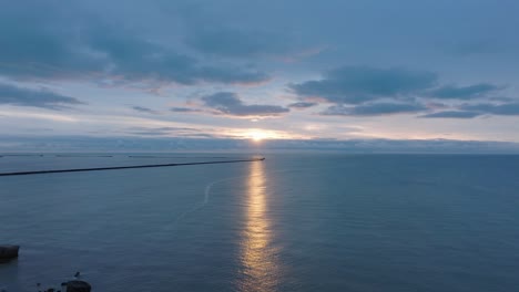 beautiful aerial establishing view of karosta concrete coast fortification ruins, vibrant high contrast sunset over calm baltic sea, winter evening, wide drone shot