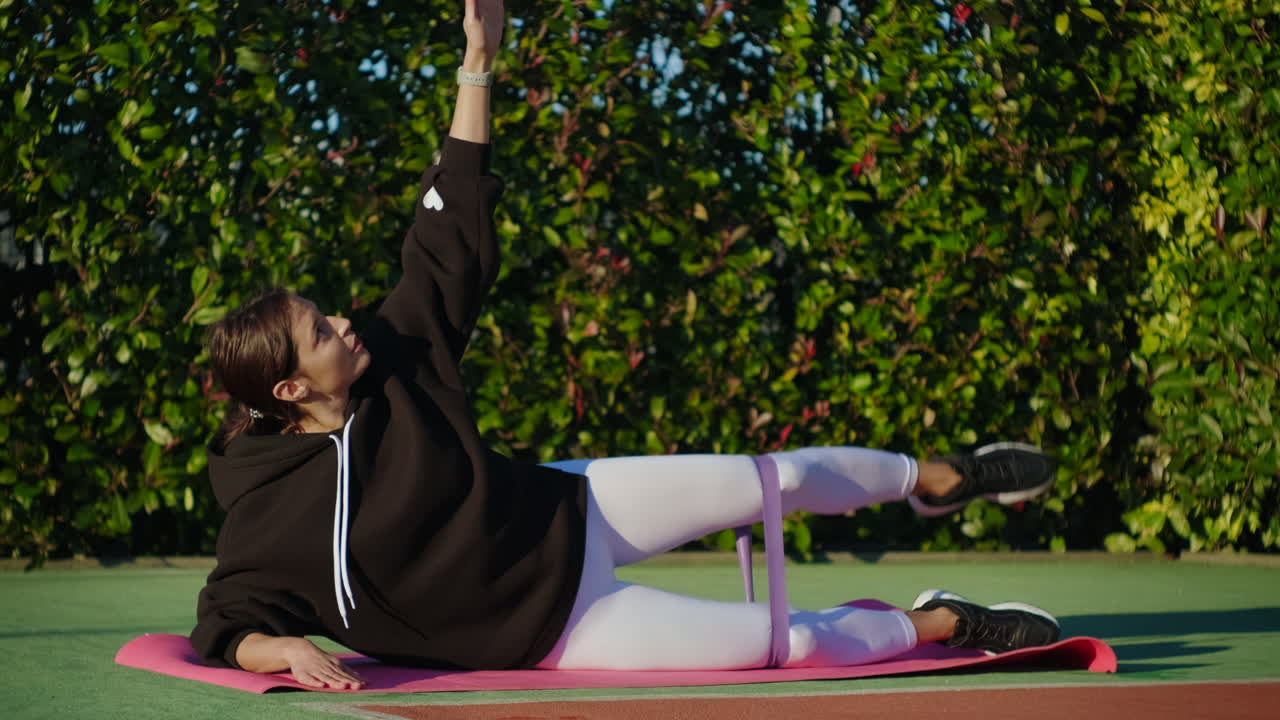 여성 이 저항 밴드 를 사용 하여 사이드 플랜크 운동 을 하고 있다