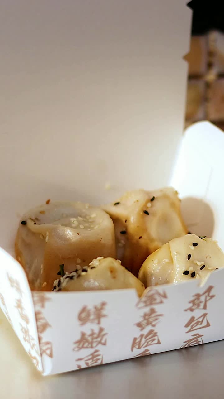 Chopsticks lifting buns from a takeout box