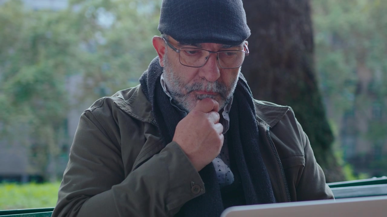 Thoughtful Senior Man Using Laptop in the Park