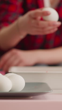 young woman takes egg to paint using ebru art technique in living room closeup slow motion. preparation for christian easter holiday celebration