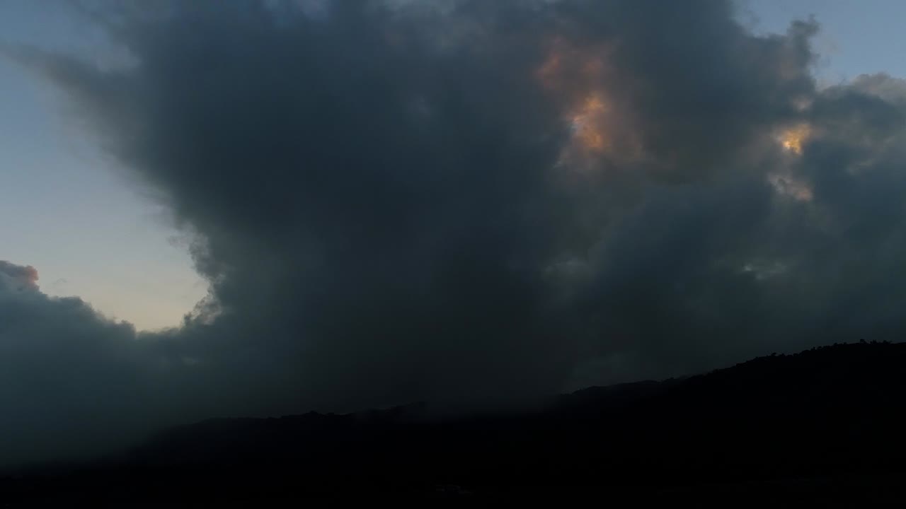Pan right shot showing misty dark clouds on sky in front of hiding sun,