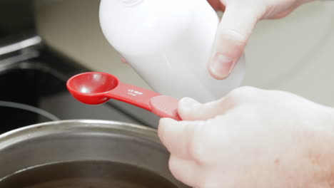 adding fragrant oil to melted wax for homemade candle project