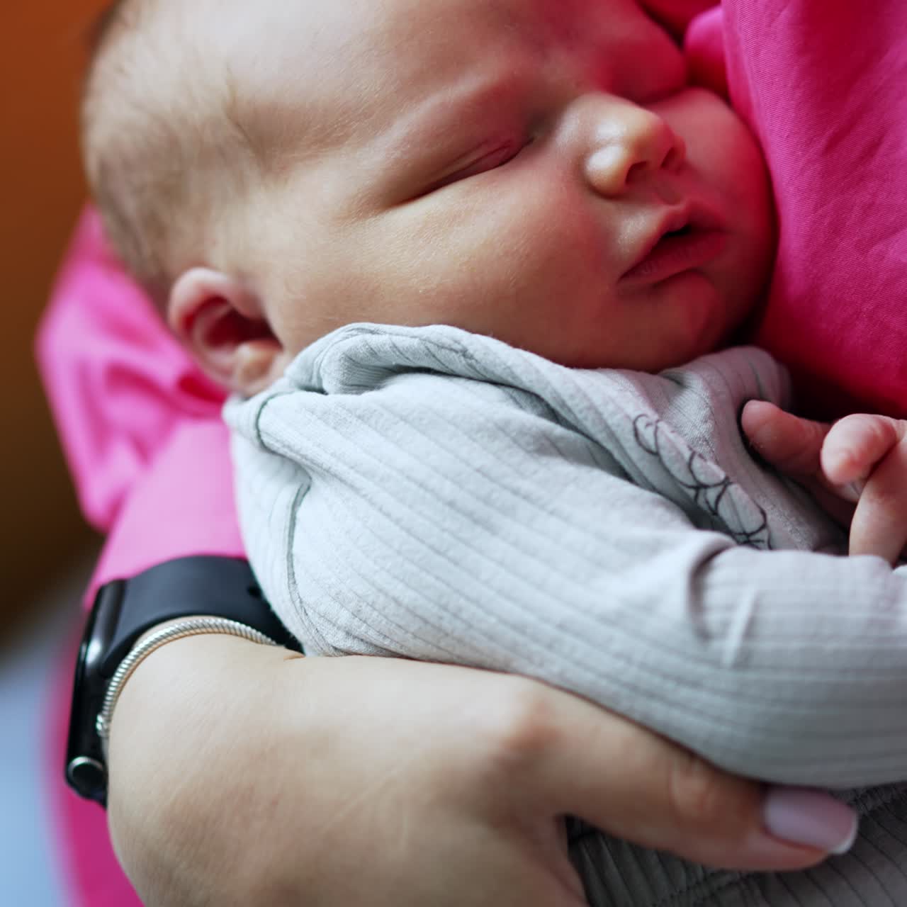 Sweet little newborn boy sleeping in mom's arms. Mother is rocking her infant baby. Top view close up