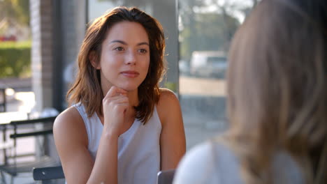 Two-female-friends-talking-over-coffee-outside-a-coffee-shop