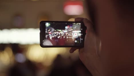 man shooting street event at night with a phone