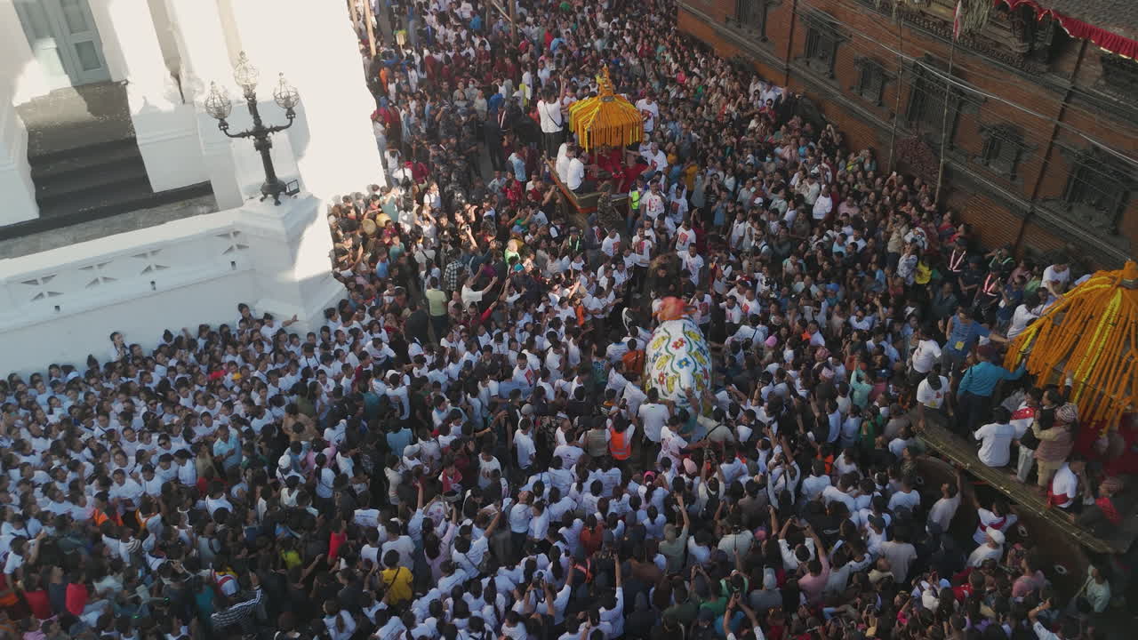 Drone shot captures Nepali citizens celebrating Indra Jatra in front of rich architectural structures of Basantapur Durbar Square Newari people perform rituals, carry chariot, and enjoy festival