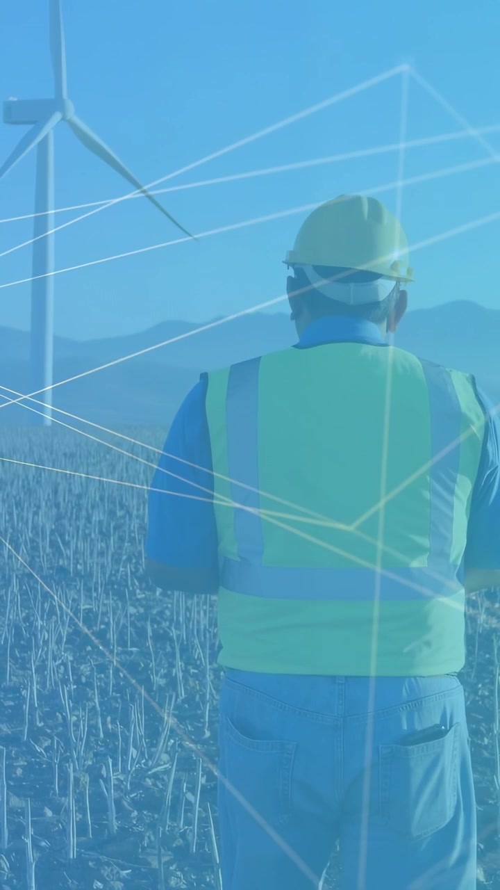 Vertical video: Man field worker walking toward turbine for energy inspection, blue lines tracking