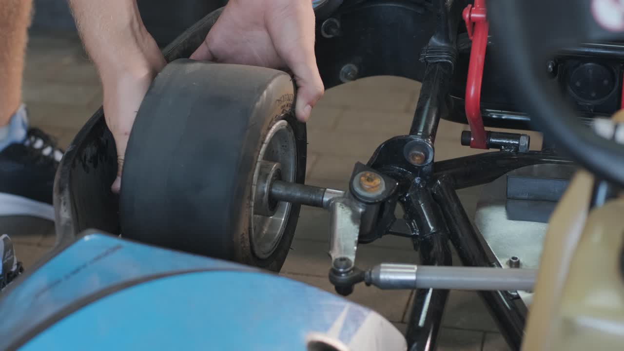 el mecánico del servicio de carreras de go kart cambia las ruedas