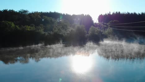 lago brumoso y bosque después del amanecer - toma panorámica bajo cables
