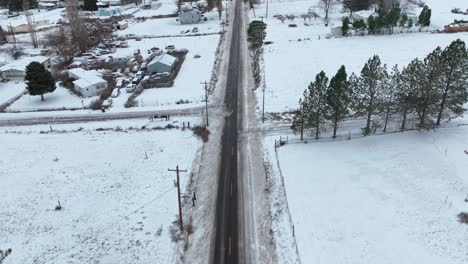 Disparo-De-Un-Dron-Inclinándose-Hacia-Arriba-Desde-El-Camino-Despejado-Para-Revelar-Tierra-Cubierta-De-Nieve-En-El-Horizonte