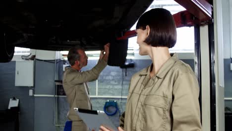 mechanic fixing a wheel while a colleague using digital tablet