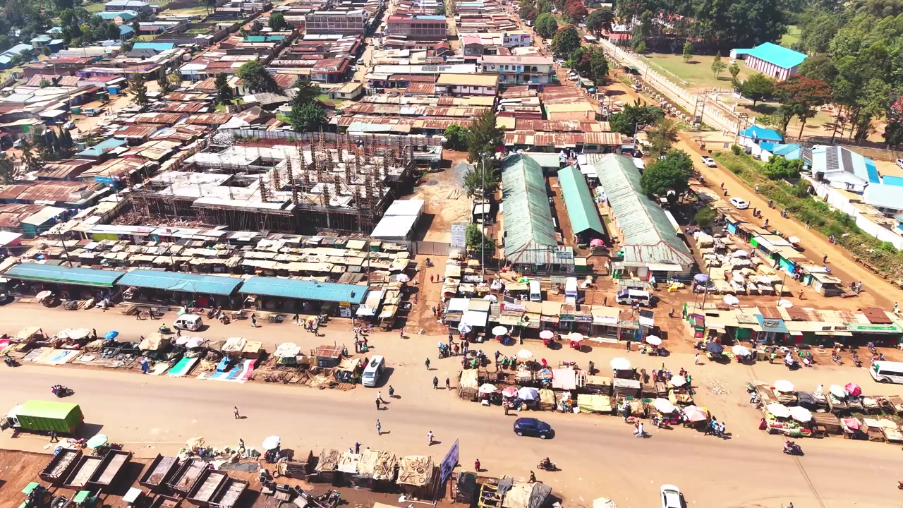 Ampia ripresa aerea che mostra lo skyline moderno di un insediamento rurale del Kenya con architetture antiche sullo sfondo e il povero distretto di baraccopoli di Kibera in primo piano
