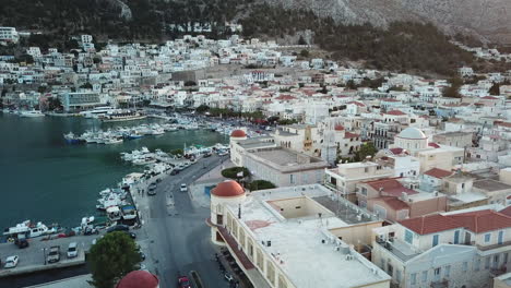 greece,kalimnos, aerial footage of the city center, starting from the harbor, goes along the seaside road, flies towards to the clock tower and the church behind the iconic municipality building,