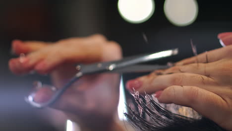 Hairdresser-cutting-hair-with-professional-scissors-and-comb-in-hairdressing-salon.-Close-up-haircutter-making-male-haircut-with-scissors-in-hairdressing-school