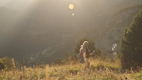 mujer rubia caminando al atardecer en las montañas de benasque, españa, plano general