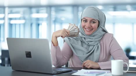 happy muslim businesswoman using money as fan