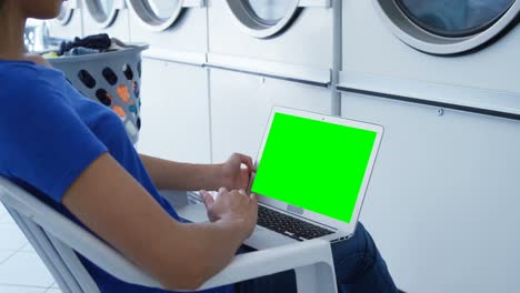 mujer usando una computadora portátil en la lavandería 4k